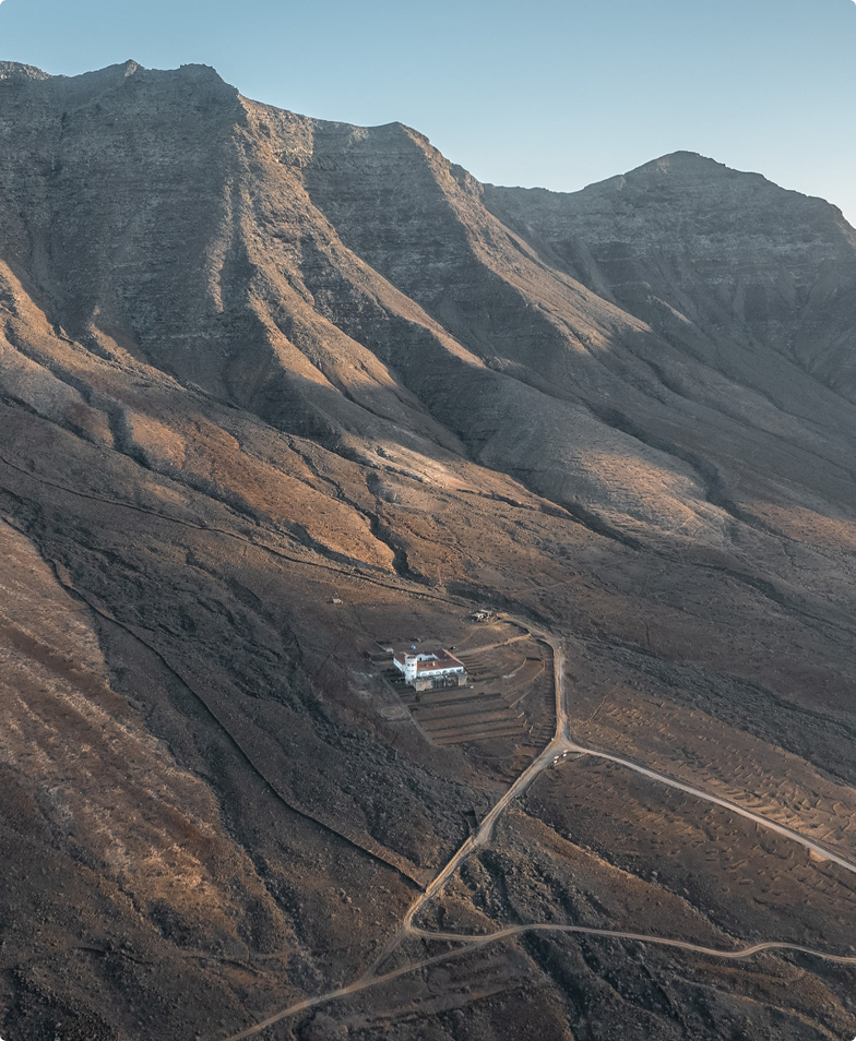 Mountaintop house, trails, and arid landscape.