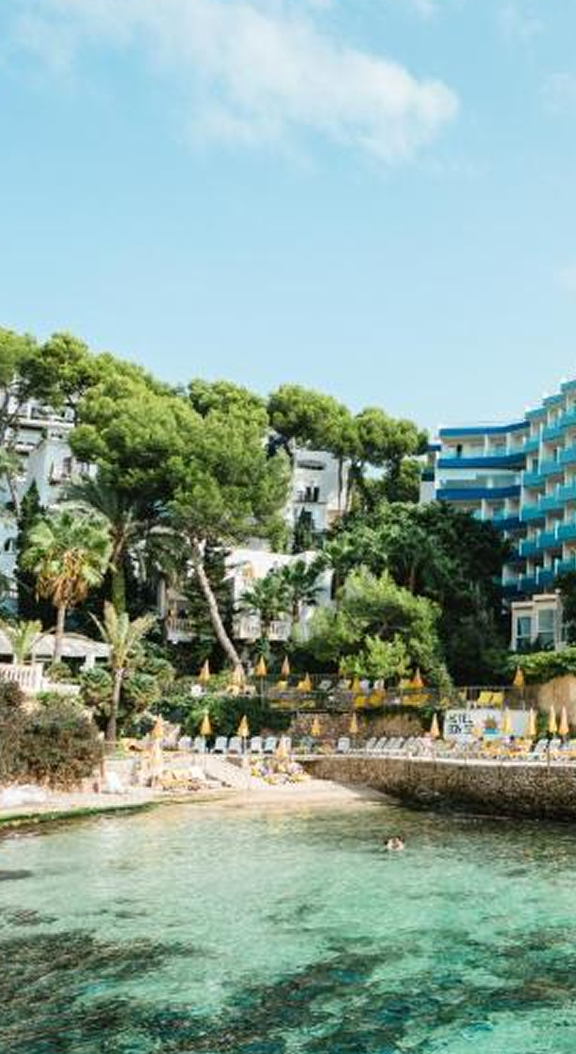 Coastal hotel nestled in lush greenery, overlooking a tranquil cove.