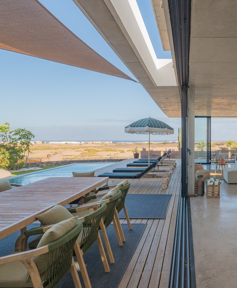Modern patio with pool, outdoor dining, and ocean view.