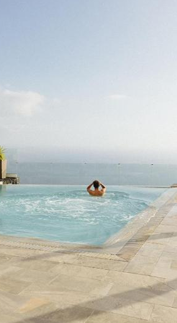 Person relaxing in oceanview infinity pool.