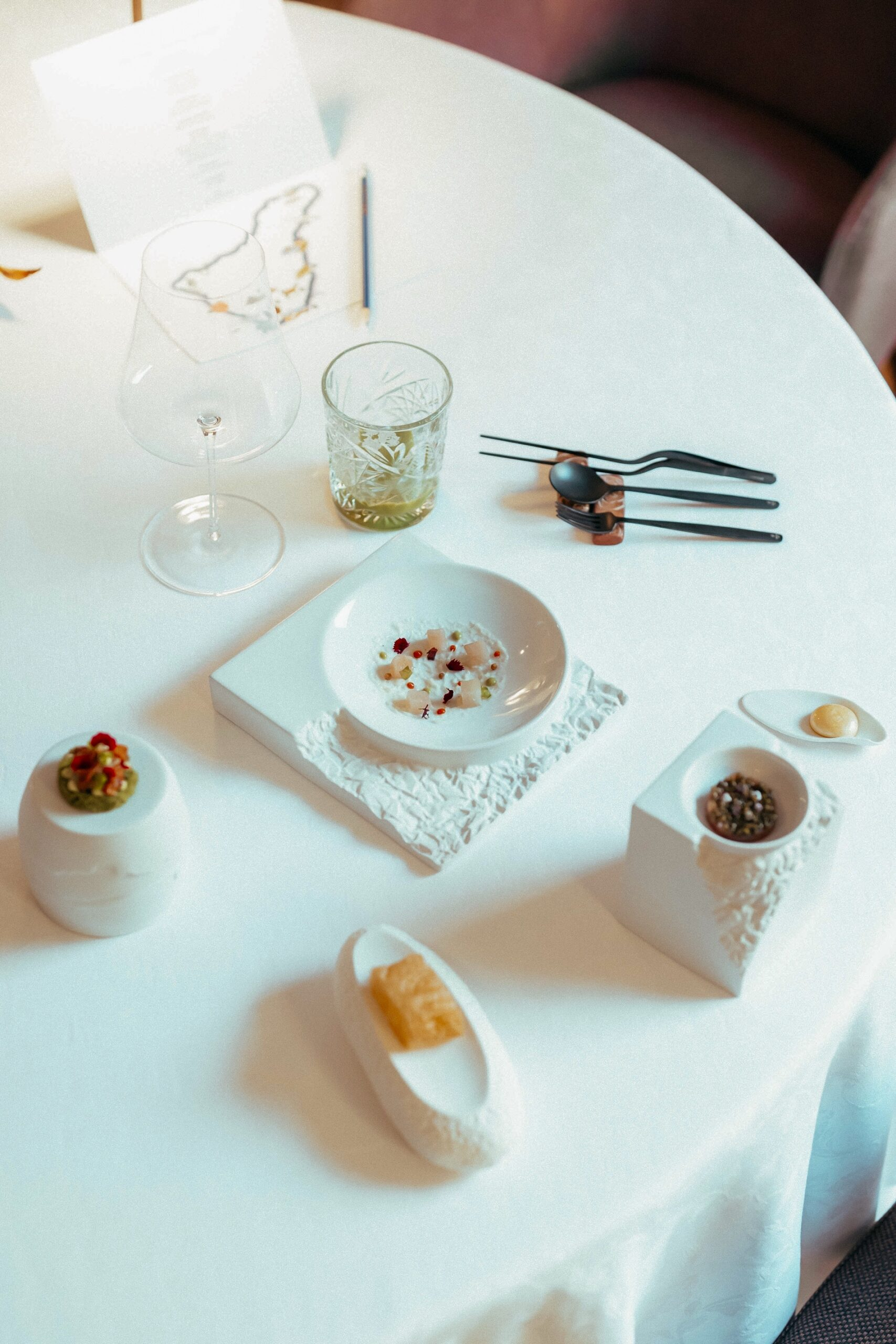 Modern gastronomy tasting menu: artistically plated dishes on a white tablecloth.