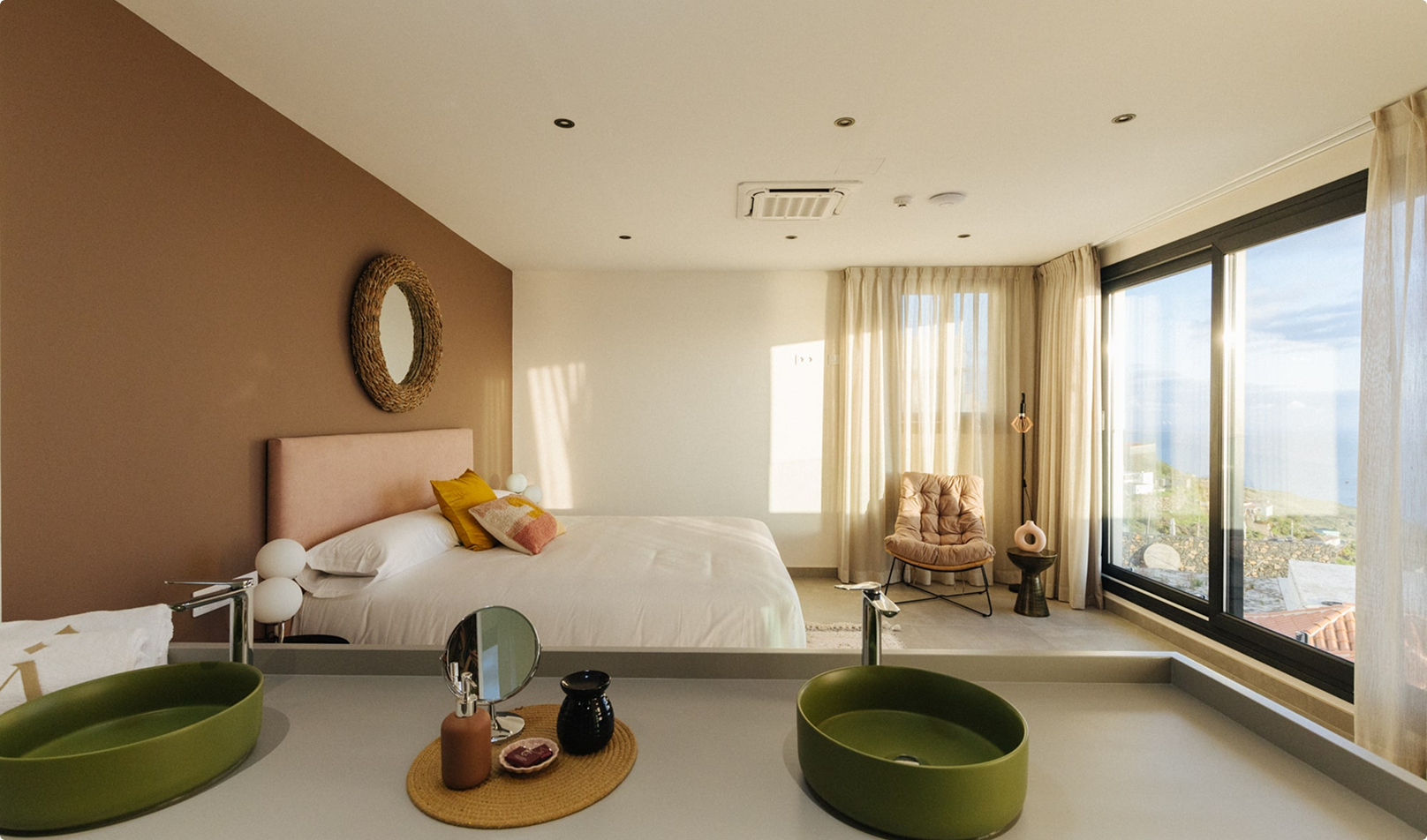 AURA Partners Anamcara Suite: Sunlit bedroom with ensuite bathroom featuring a double sink and ocean view.