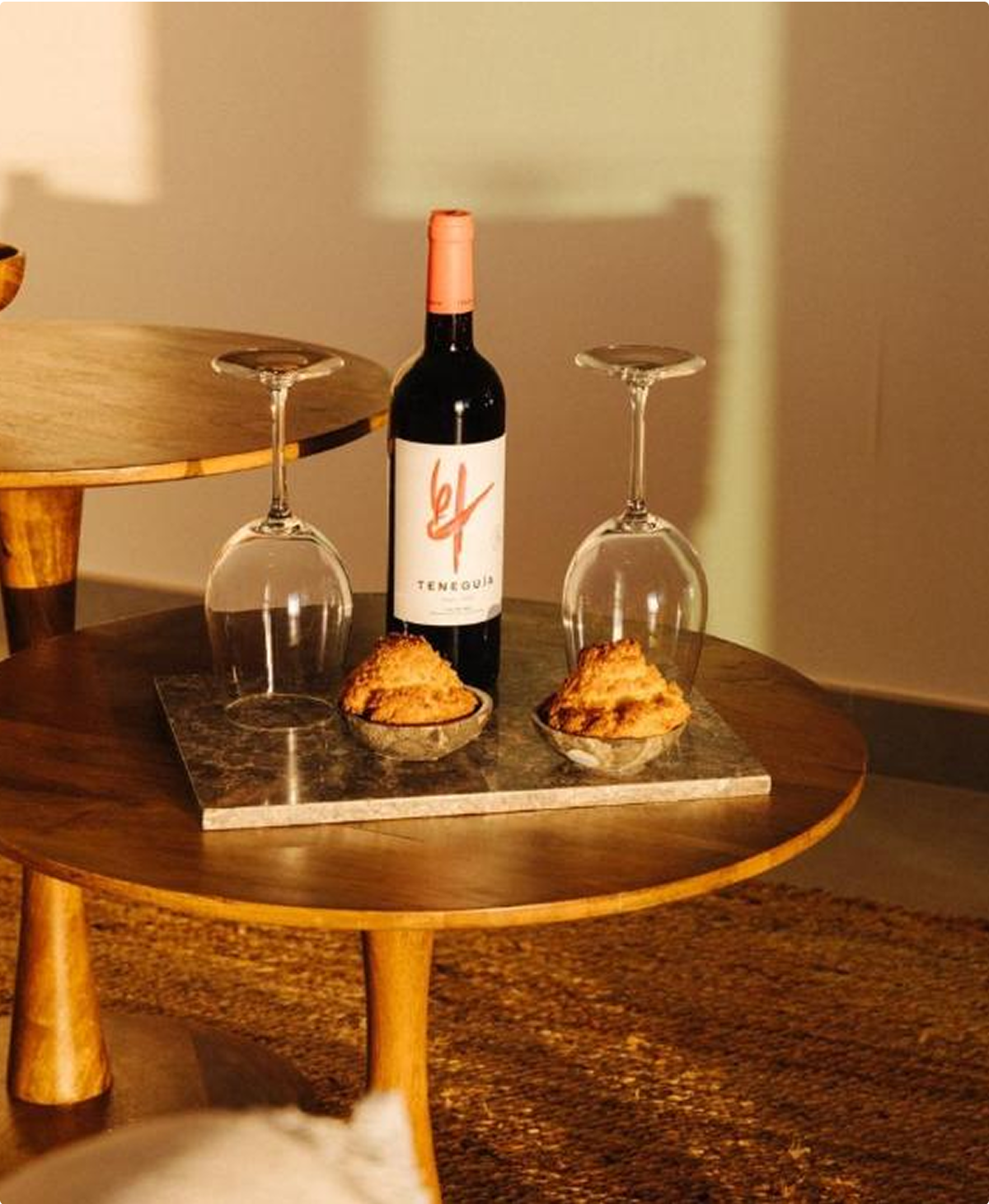 Teneguía wine, two glasses, and pastries on a coffee table.