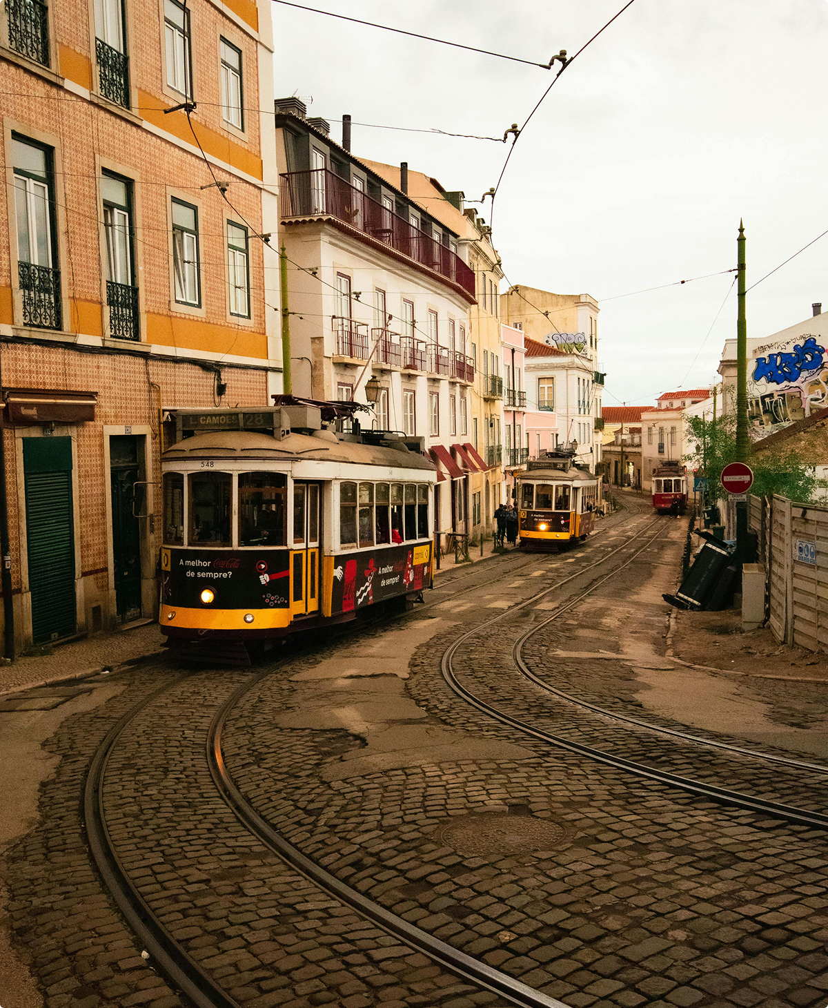 Lisbon trams on cobblestone street; AURA Partners collaboration.